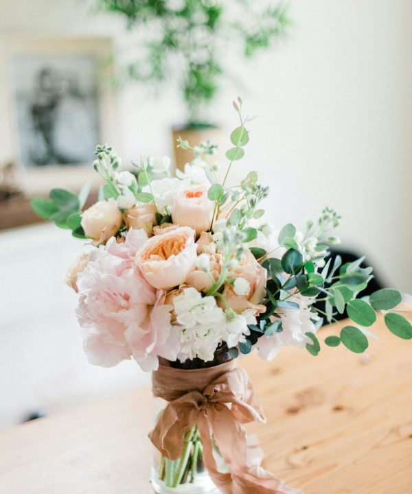 Pale pink and cream roses with greenery, tied together with a fabric ribbon.