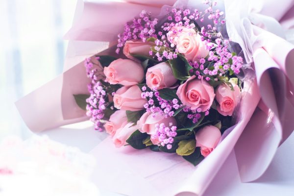 Soft pink roses and purple accents in light paper wrapping.
